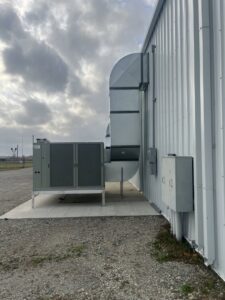 A large commercial HVAC unit with extensive ductwork installed on the side of a building by Alpha HVAC LLC in Alexandria, LA.