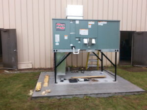 A large commercial RUUD HVAC unit installed on a stand outside a building by Action Mechanical LLC in Eau Claire, WI.