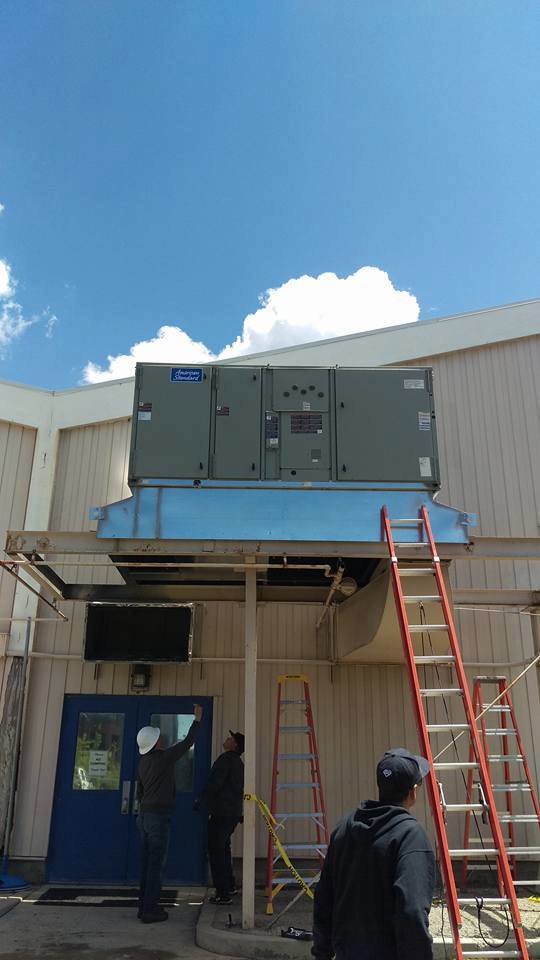 Workers installing a large commercial HVAC unit on an elevated platform for Any Climate Mechanical HVAC in Sandy, UT.