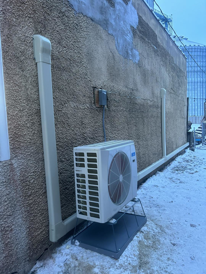 A commercial outdoor HVAC unit installed next to a building in winter by BRY Heat and Air in Elgin, MN
