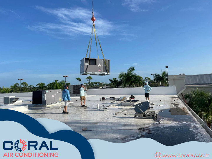 Technicians from Coral Air Conditioning installing a commercial HVAC unit with a crane on a rooftop in Cape Coral, FL.