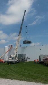 A crane lifting a large commercial HVAC unit onto a building roof by Michael Savage-Lanz Heating & Cooling in Champaign, IL