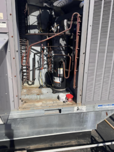 The interior of a commercial HVAC unit showing a compressor and coils, inspected by Mead Heating and Cooling in Kansas City, MO.