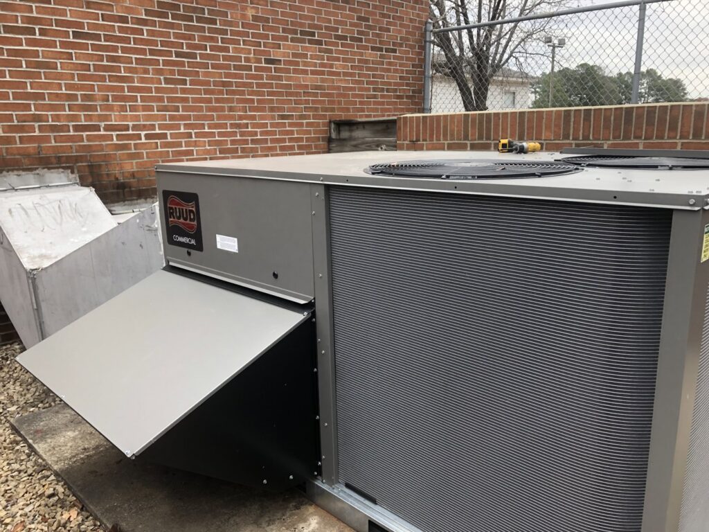 A Ruud commercial HVAC unit with an open access panel, indicating service or repair by Deon Arnold Heating & Air Conditioning in Fayetteville, NC
