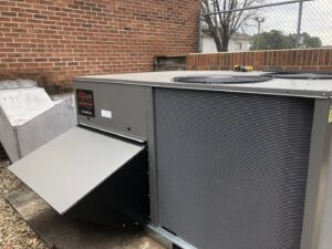 A Ruud commercial HVAC unit with an open access panel, indicating service or repair by Deon Arnold Heating & Air Conditioning in Fayetteville, NC