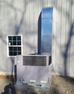 A large commercial HVAC unit with vertical ductwork installed on the exterior of a building by Fusion Heat and Air in Fort Smith, AR.