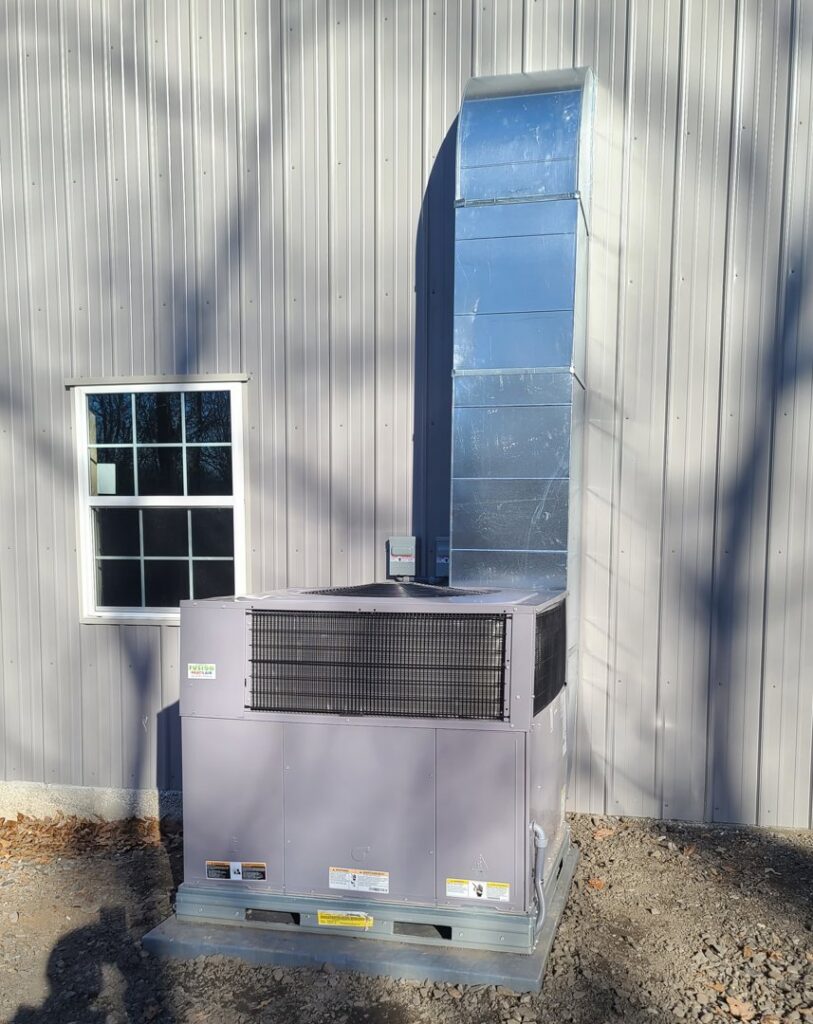 A large commercial HVAC unit with vertical ductwork installed on the exterior of a building by Fusion Heat and Air in Fort Smith, AR.