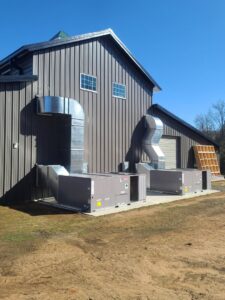 Two commercial HVAC units with extensive ductwork installed on the exterior of a building by Fusion Heat and Air in Fort Smith, AR.
