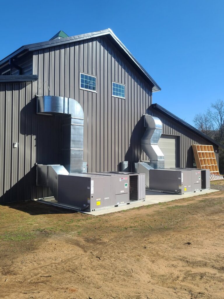 Two commercial HVAC units with extensive ductwork installed on the exterior of a building by Fusion Heat and Air in Fort Smith, AR.