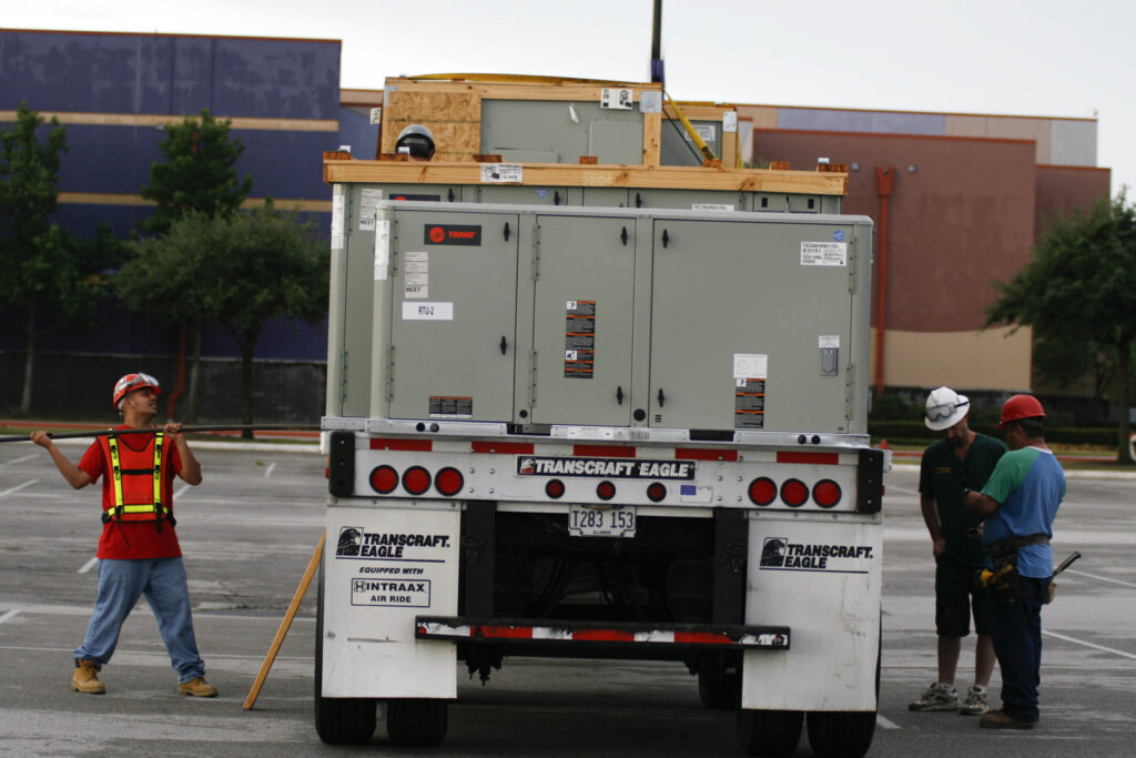 Commercial HVAC units loaded on a trailer with workers, ready for installation by Chapman Air and Heat in Dallas, TX
