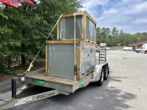 Large commercial HVAC units secured on a trailer for transport by Underwood Heating and Air Conditioning in Phenix City, AL