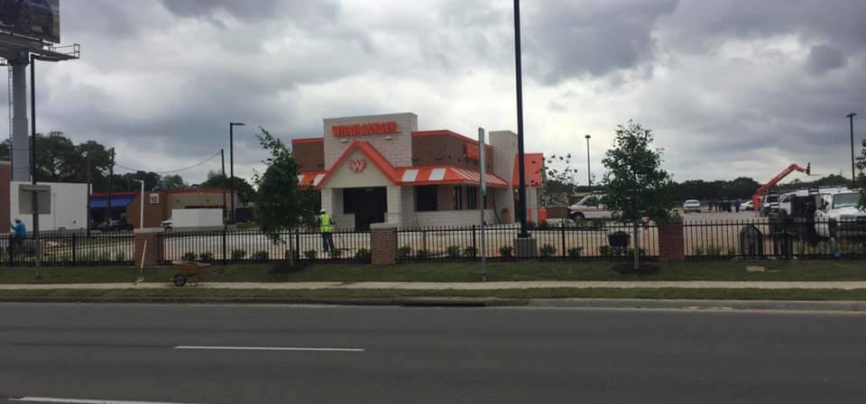 A black ornamental iron fence with brick pillars installed around a commercial property by Texas Fence and Iron Co. in Houston, TX.