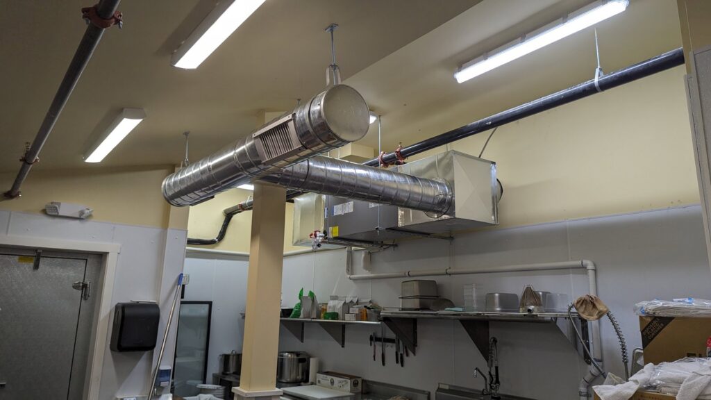 Exposed HVAC ductwork and an air handler installed in a commercial kitchen by WARM Global HVAC in East Providence, RI.