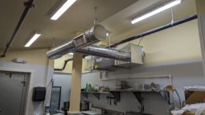 An installed HVAC system with spiral ductwork and an air handler in a commercial kitchen by WARM Global HVAC in East Providence, RI