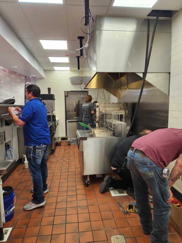 Technicians installing or servicing commercial kitchen ventilation systems for OKIE Heating and Cooling in Tulsa, OK.
