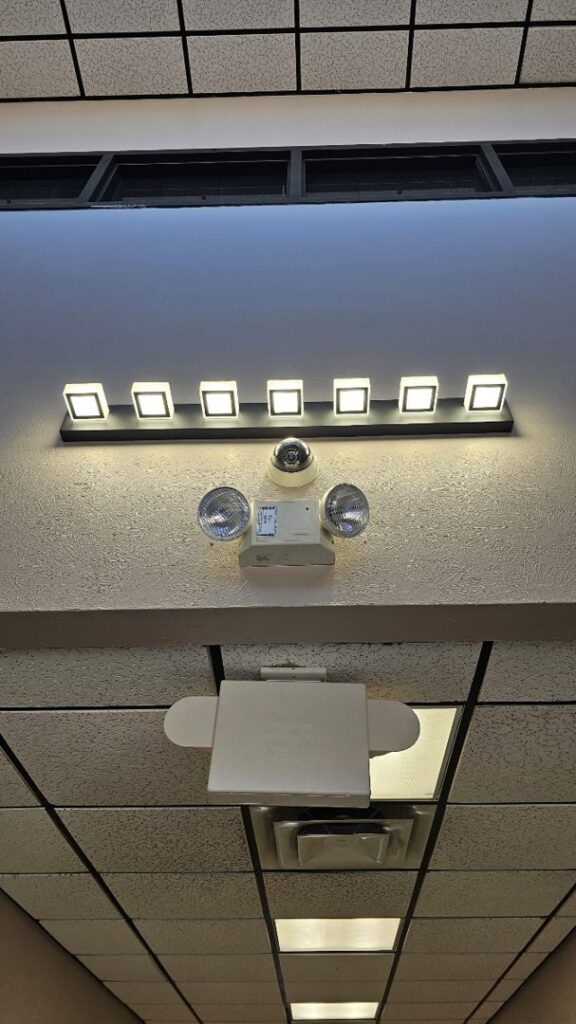 Commercial lighting, emergency light, and security camera installed on a ceiling by V Electrical LLC in Albuquerque, NM.