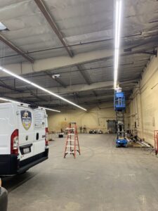 An electrician from Positive Electricians installing commercial lighting in a large space in Van Nuys, CA.