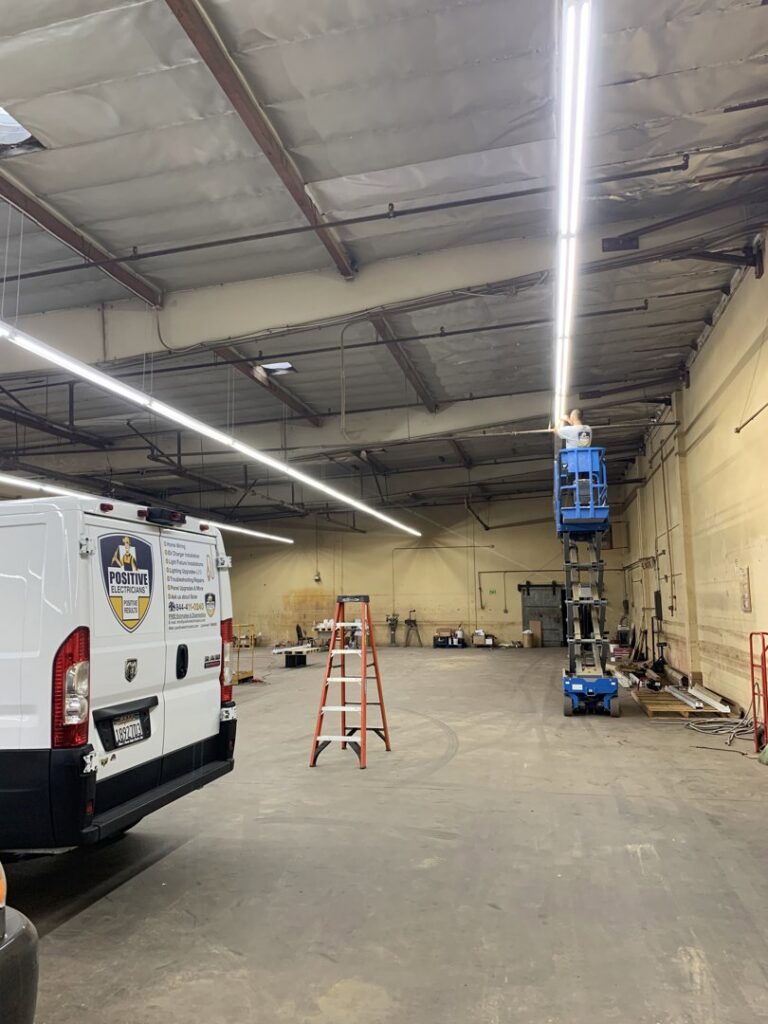 An electrician from Positive Electricians installing commercial lighting in a large space in Van Nuys, CA.