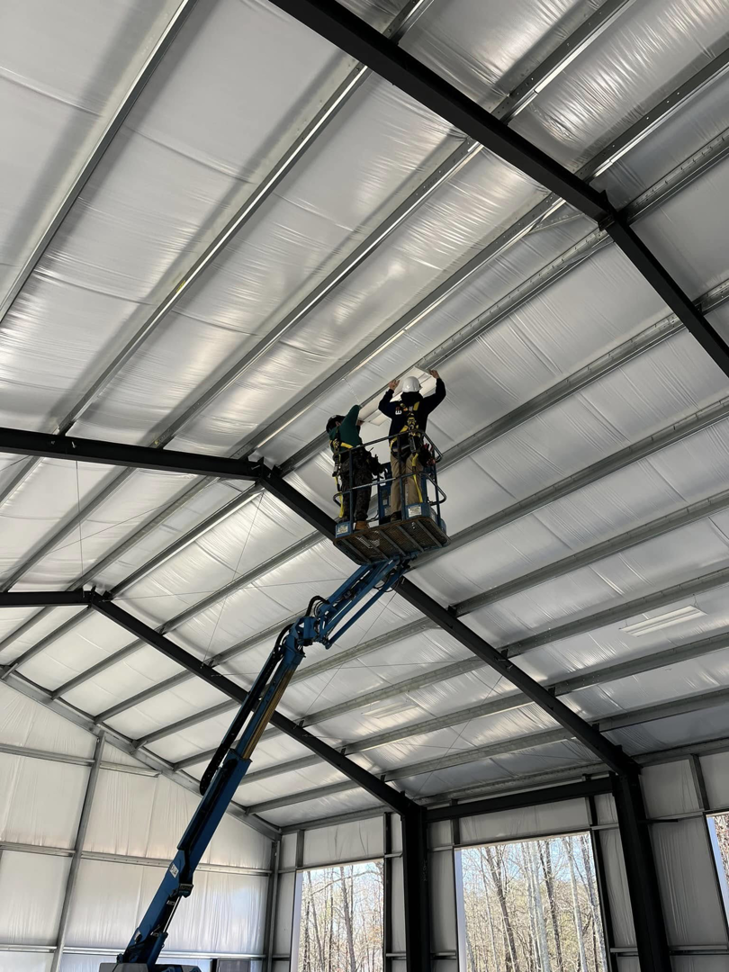 Electricians installing commercial lighting fixtures on a high ceiling for Hilman Electric LLC in Greenville, SC.