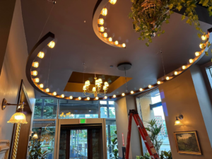 Commercial decorative lighting and a chandelier installation with a ladder, performed by P&E Electric in Denver, CO.