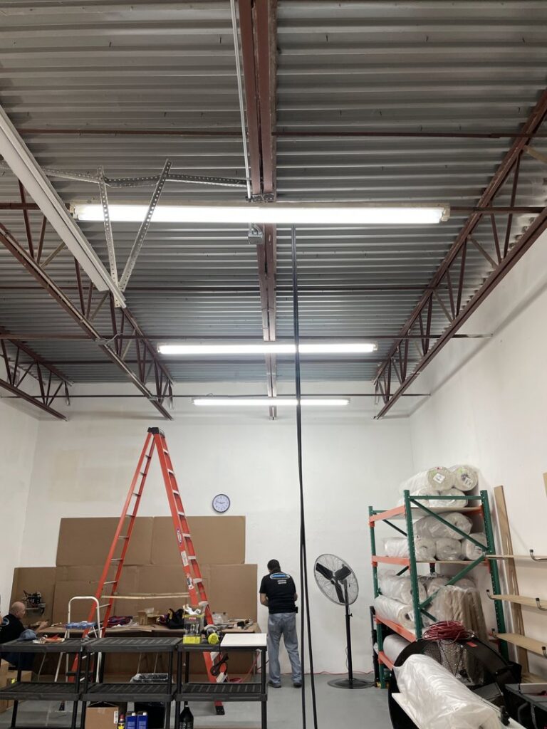 An electrician installing or maintaining commercial fluorescent lighting in a large space for MG ELECTRIC INC in Lauderhill, FL
