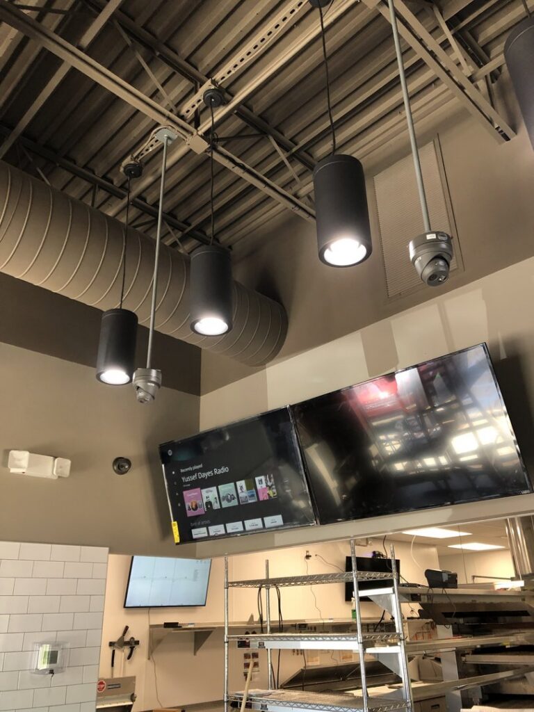 Commercial ceiling with pendant lighting, security cameras, and mounted TVs, installed by PTech Installs in Columbus, GA.