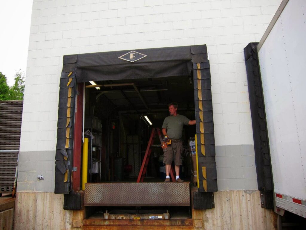 A contractor working on a commercial loading dock door and equipment for AJK Door Services in Duluth, MN.