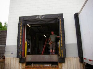 A contractor working on a commercial loading dock door and equipment for AJK Door Services in Duluth, MN.