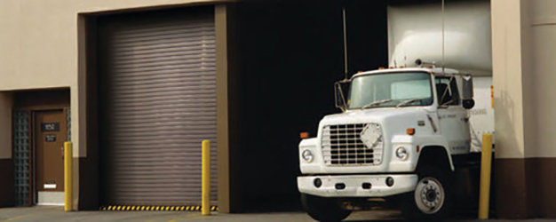 A commercial loading dock with a roll-up garage door and a truck by Overhead Door Company of Knoxville in Knoxville, TN