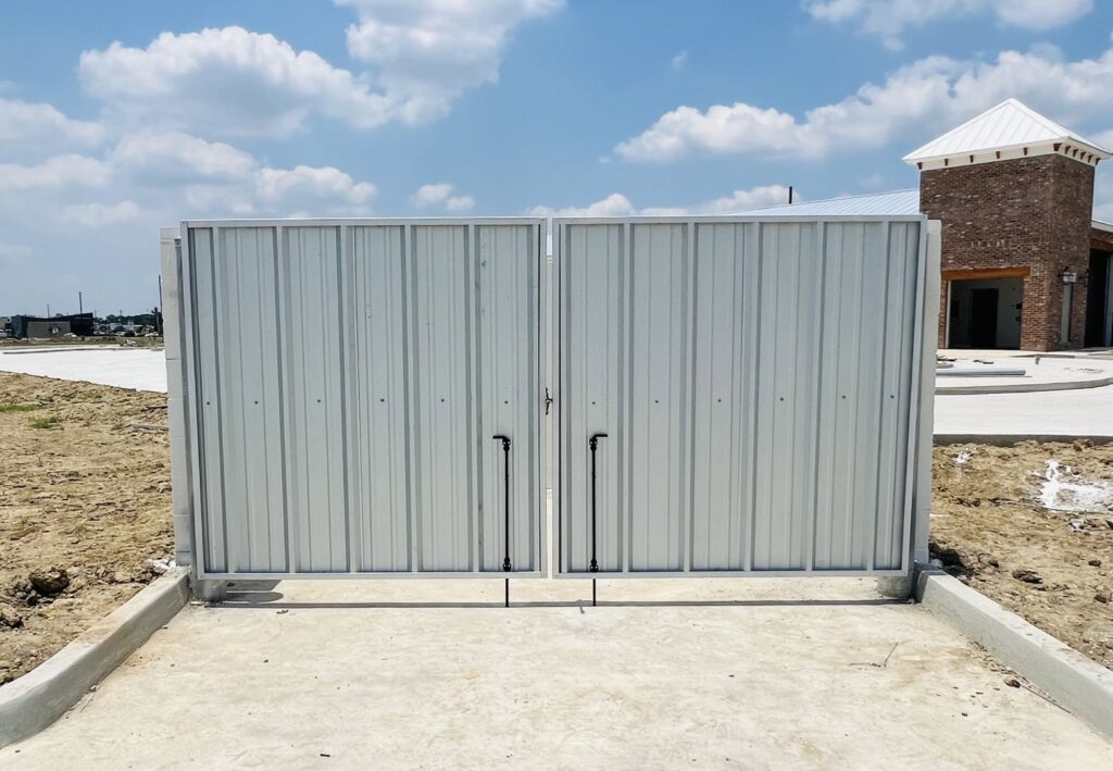 A large commercial metal dumpster enclosure with double gates on a new construction site by Capitol Fencing in Baton Rouge, LA.