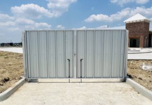 A large commercial metal dumpster enclosure with double gates on a new construction site by Capitol Fencing in Baton Rouge, LA.