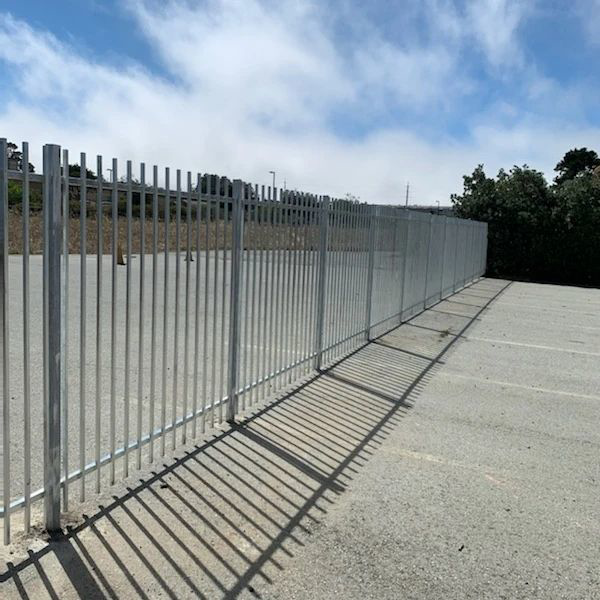 A long commercial metal picket fence bordering a parking lot, installed by Fierro Iron Works Inc. in San Francisco, CA.