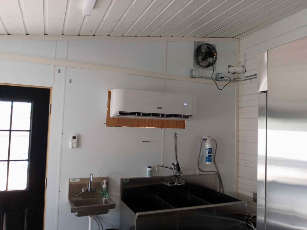 A commercial indoor mini-split air conditioning unit installed above sinks in a workspace, by Jones Heating and Refrigeration in Dickinson, ND.
