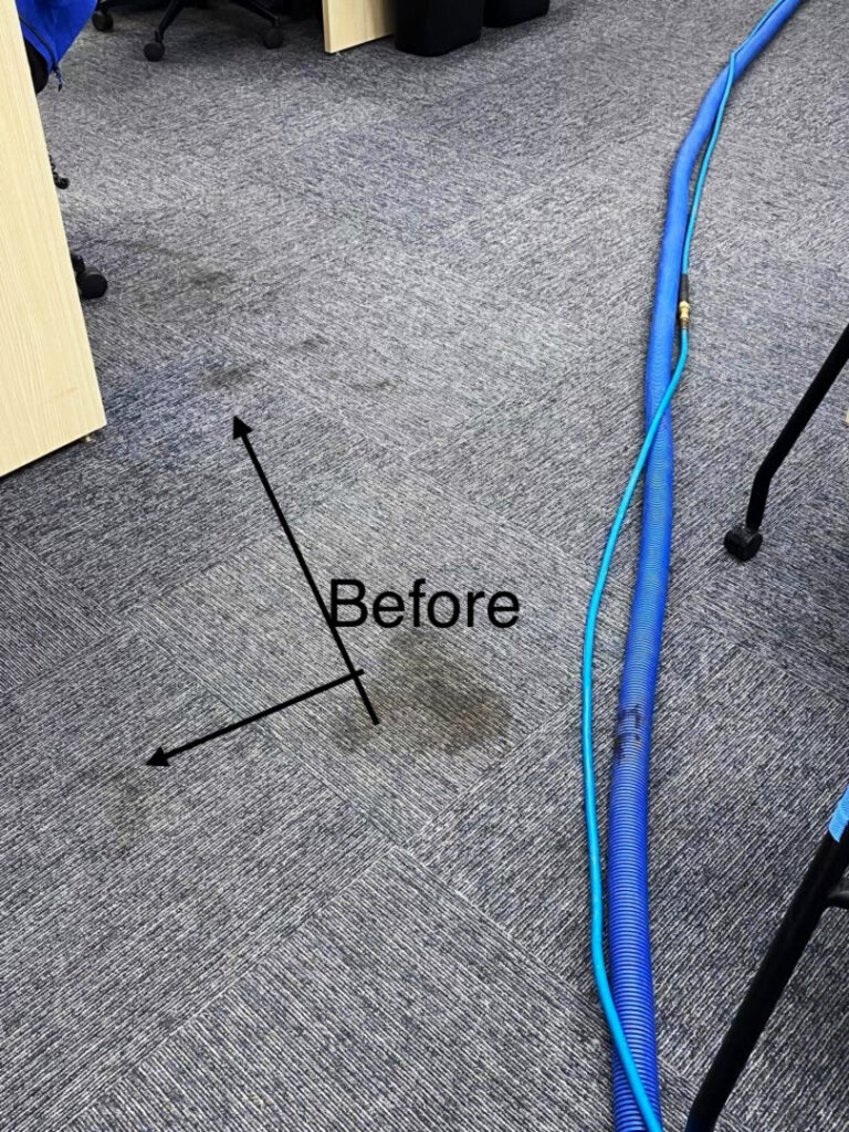 A stained commercial office carpet before cleaning, with equipment visible, by On The Spot Carpet Cleaning in Erie, PA.
