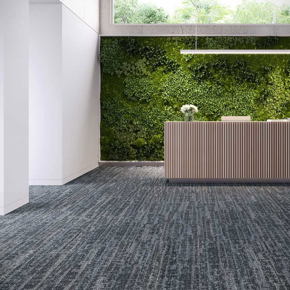 A modern commercial office reception area featuring patterned blue and grey carpet installed by Eastpointe Interiors in Caledonia, MI.