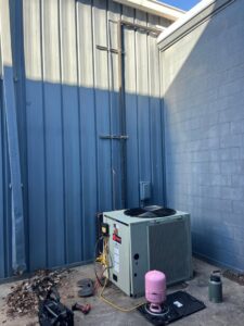 An outdoor commercial air conditioning unit being serviced by Pro-Cool Air Conditioning & Heating in Blue Springs, MO.