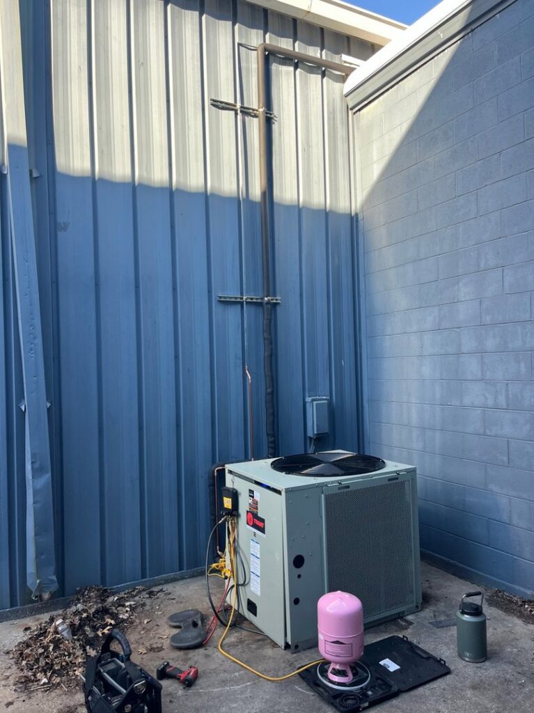 An outdoor commercial air conditioning unit being serviced by Pro-Cool Air Conditioning & Heating in Blue Springs, MO.