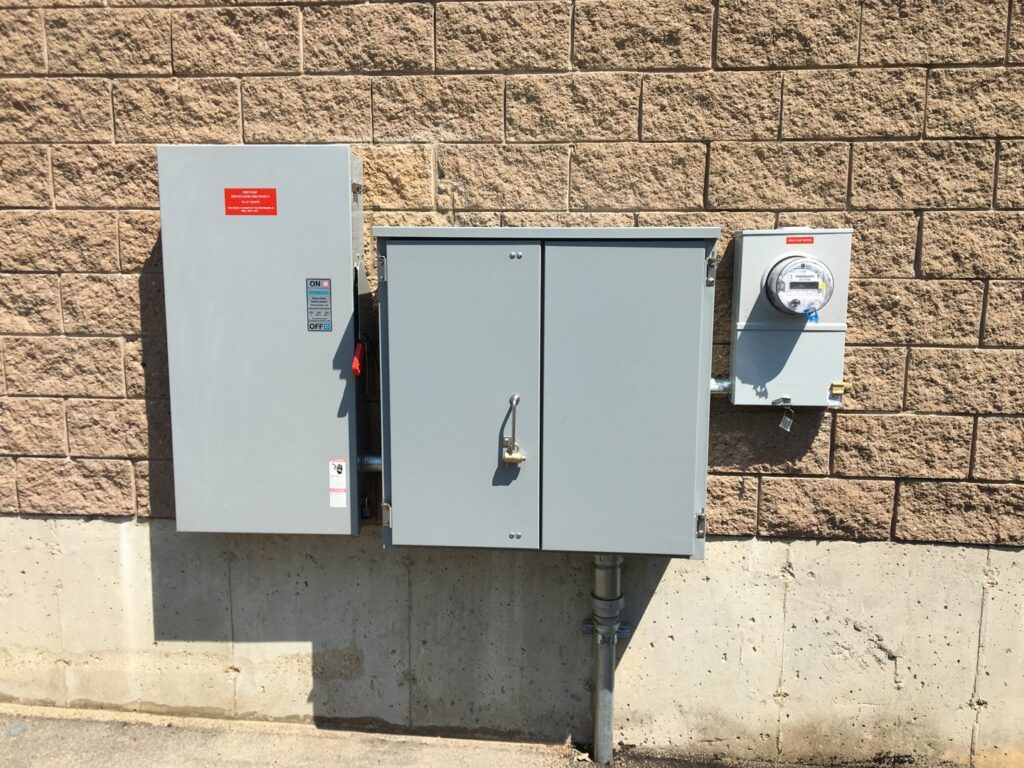 Outdoor commercial electrical panels and meter installed on a brick wall by Richard Sullivan Licensed Electrician in Brockton, MA.