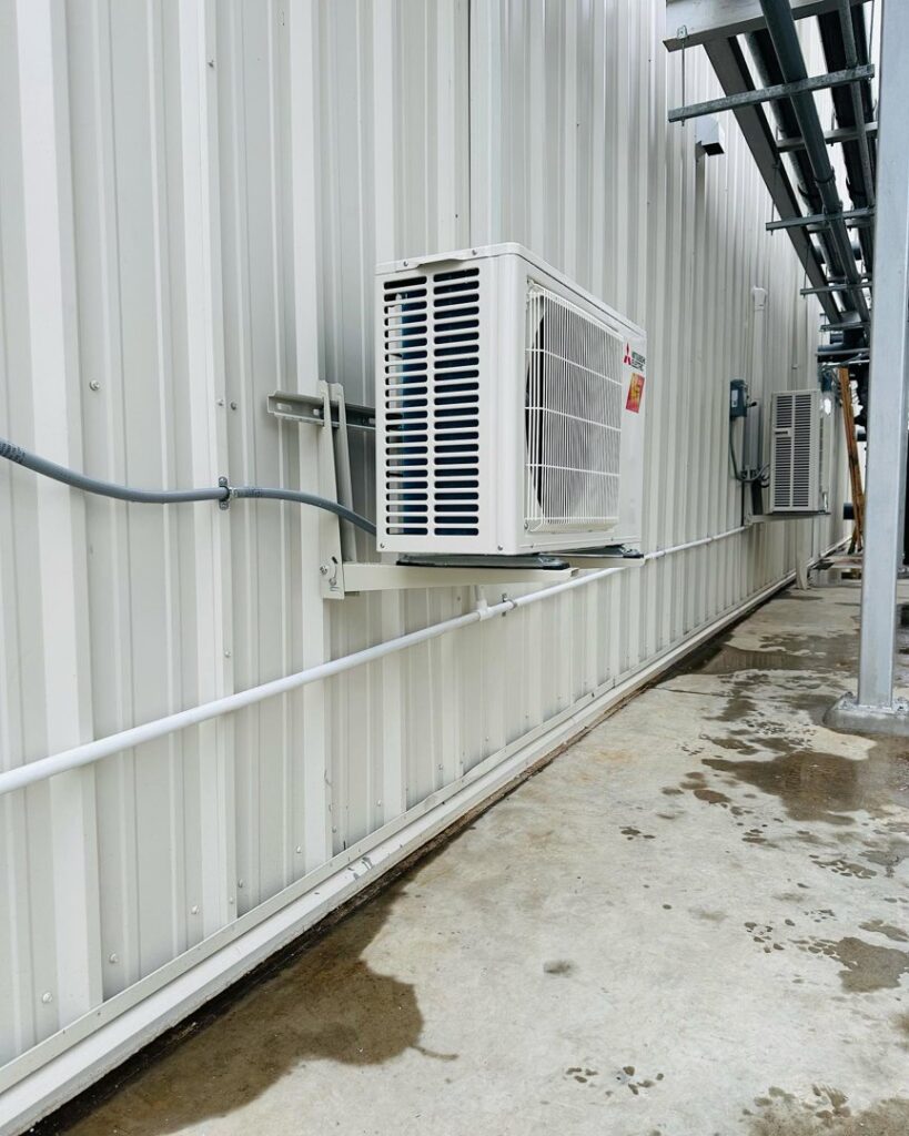 An outdoor HVAC unit mounted on the side of a commercial building by Deboque Duct Design Corp. in Staten Island, NY