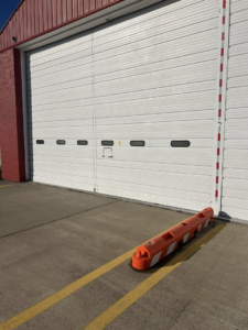 A large white commercial overhead garage door on a red building by Codiwayne Construction & Door in South Bend, IN.