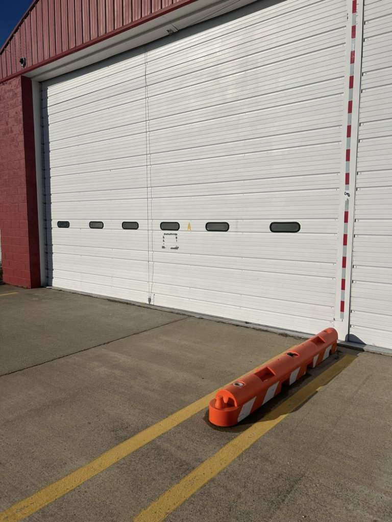 A large white commercial overhead garage door on a red building by Codiwayne Construction & Door in South Bend, IN.
