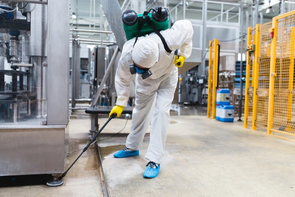 A commercial pest control technician in a hazmat suit spraying in an industrial facility for Bug Doctor in Las Vegas, NV.