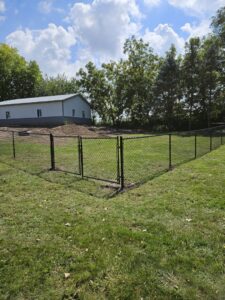 A black chain-link fence with a gate securing a commercial property, installed by JM Fence Works in Davenport, IA.