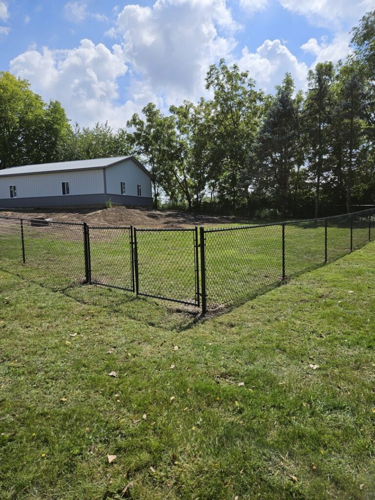 A black chain-link fence with a gate securing a commercial property, installed by JM Fence Works in Davenport, IA.