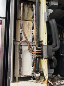 Internal view of dirty copper refrigeration coils and lines in a commercial unit, indicating service by Commercial Kitchen Services, LLC of Watertown, SD.
