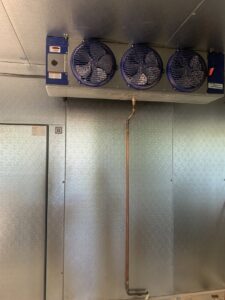 An interior view of a commercial refrigeration evaporator unit with three fans by Alpha HVAC LLC in Alexandria, LA.