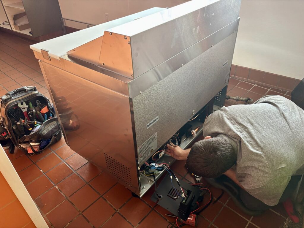 An HVAC technician performing commercial refrigeration repair on a unit for Polar Air Heating and Cooling in Omaha, NE