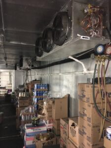A commercial refrigeration unit with gauges attached, indicating service by West Tennessee Heat & Air in Memphis, TN