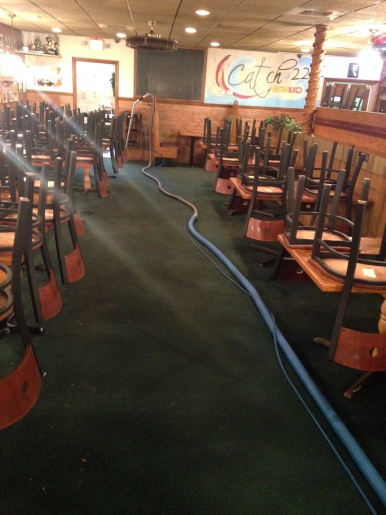 Commercial carpet cleaning setup in a restaurant with chairs stacked, by On The Spot Carpet and Upholstery Cleaning in Warren, MI.