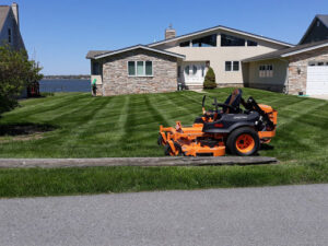 A commercial riding lawn mower parked on a perfectly striped lawn by John's Lawn Care Service's in Saint Petersburg, FL